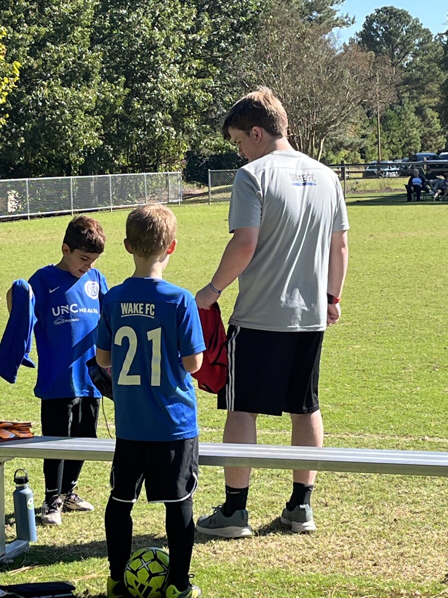 Coach Will with Wake FC U11 players on the sideline